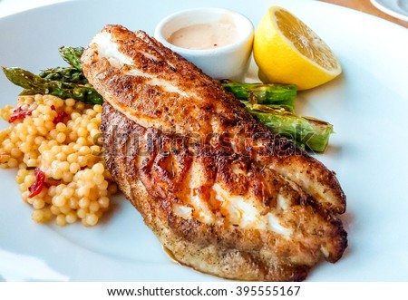 Blackened fish dinner with couscous asparagus and lemon Royalty-Free Stock Photo #395555167