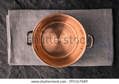 Copper pot on the dark stone table top view Royalty-Free Stock Photo #395567689
