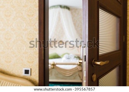 Half opened door of a bedroom. Hotel bedroom door half open. Hotel room welcome guests. Opening door closeup. Door handle. Privacy, intimacy concept. Entrance to the hotel bedroom. 