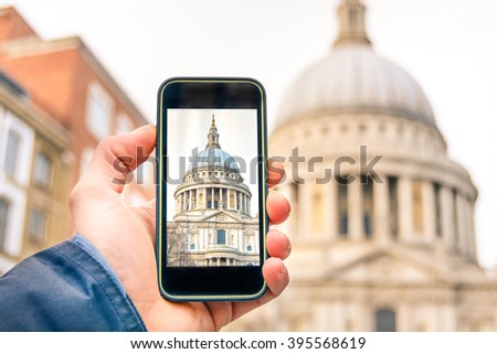 Modern travelers visit St. Paul's Cathedral in London taking souvenir photo using smartphone. Hand holding phone for take picture for social media uploading. Travel concept and new technologies trends