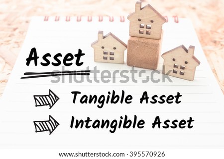 word asset tangible and intangible on note paper small wooden house background Royalty-Free Stock Photo #395570926
