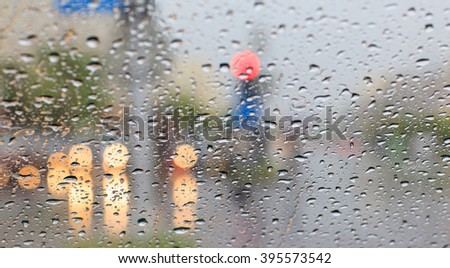 Rain drops on window with traffic light and road sign
