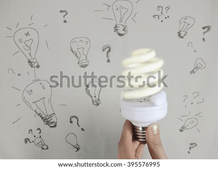 Fingers holding hands in front of a modern energy-saving lamp background pictures other lamps