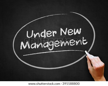 A hand writing 'Under New Management' on chalkboard.