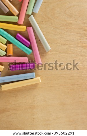 Group colored pastel chalks in a chaotic manner on a wooden background