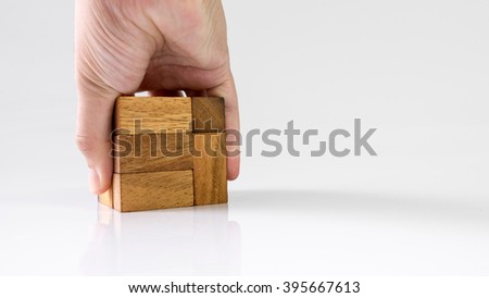 Human hand touching and assembling wooden cube puzzle. Isolated on white background. Slightly de-focused and close-up shot. Copy space.