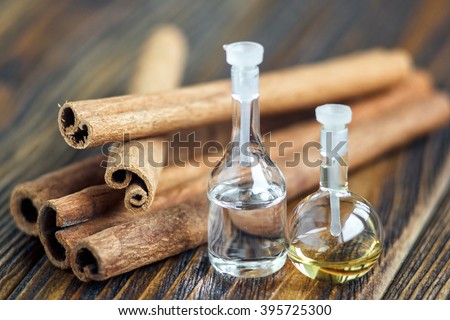 Essential oil in glass bottle with cinnamon sticks on wooden background. Beauty treatment. Spa concept. Selective focus.