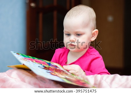 Little girl carefully considering the book in the room