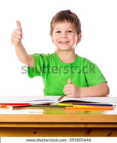 Creative little boy at the table with thumb up sign, isolated on white