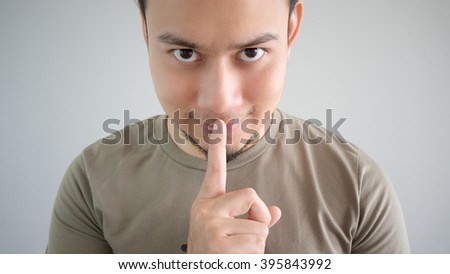 Asian man is telling a secret. Do not tell anyone.