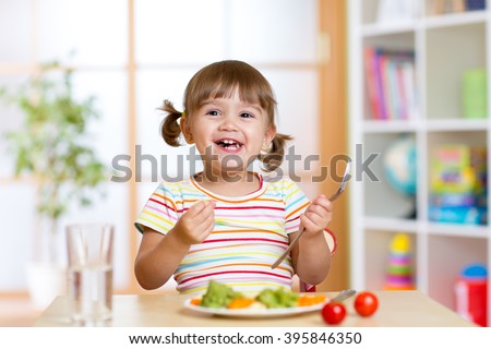 Happy child girl eating vegetables. Healthy nutrition for kids Royalty-Free Stock Photo #395846350