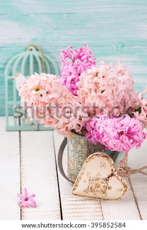 Background with  pink hyacinths in vase,  decorative  heart  on white wooden planks against turquoise wall. Selective focus. 
