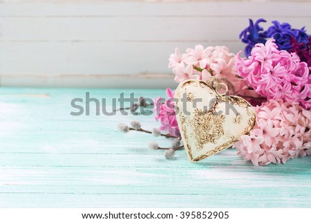 Hyacinths  and  decorative heart  on  turquoise  wooden background against white wall. Selective focus. Place for text.