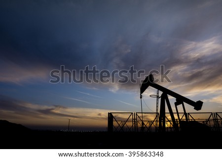 Silhouette of crude oil pump and cloudy sunset in the oil field.
