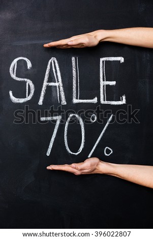 Two hands showing seventy percent sale drawn on blackboard with chalk