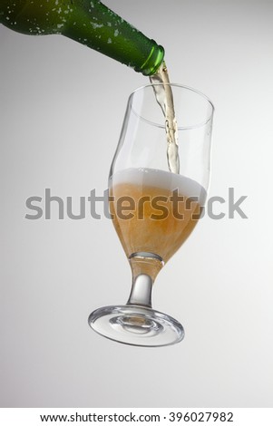 Pouring ice cold beer from bottle into glass