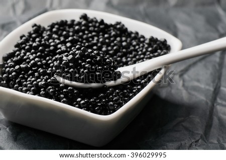 spoon of black caviar in a white bowl horizontal