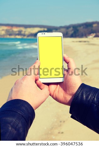 White smart phone on the background Black Sea in male hands, holding, instagram effect