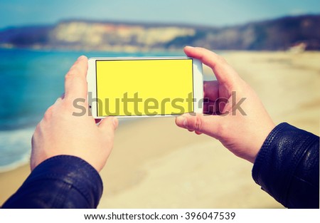 White smart phone on the background Black Sea in male hands, holding, instagram effect
