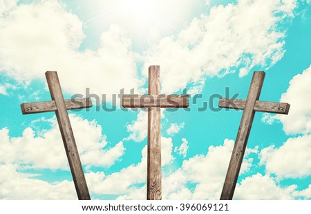 Old brown wooden cross, with sun flash on clouds background