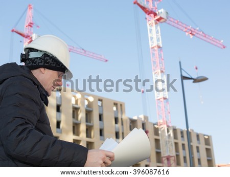 An engineer on a construction site with cranes