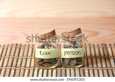 Coins in jar. Writing Tax Pension on two jar with wooden pallet background. Selective focus with shallow depth of field.