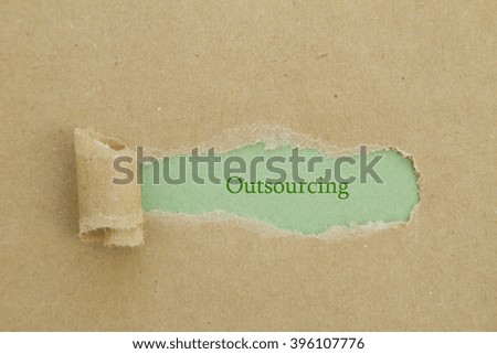 Outsourcing word written under torn paper.