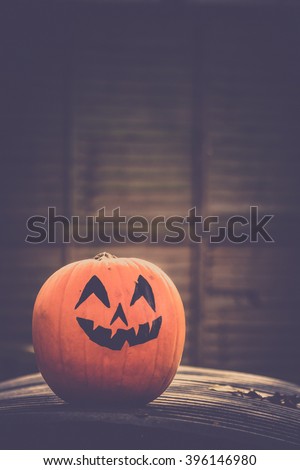 Large pumpkin with a scary face drawing on it