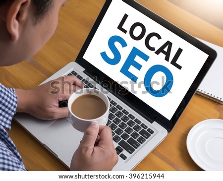 Local SEO Concep Businessman at work. Close-up top view of man working on laptop while sitting at the wooden desk , coffee