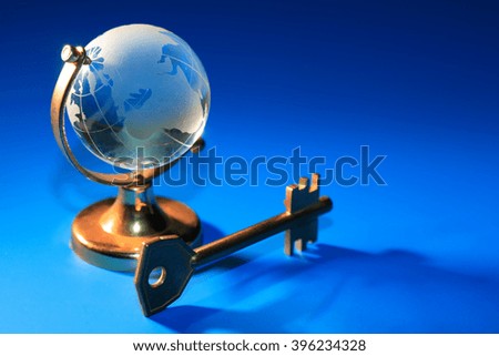Glass globe near key on blue background with free space