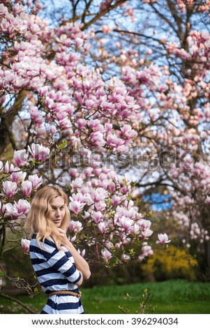 girl stands near a flowering magnolia tree