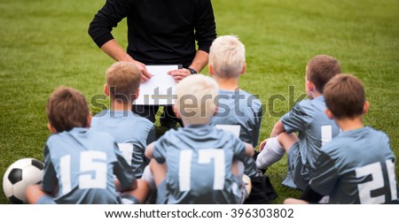 Coach Encouraging Boys Soccer Team. Soccer Football Team with Coach at the Stadium. Coach with Youth Soccer Team. Boys Listen to Coach's Instructions. Coach Giving Team Talk Royalty-Free Stock Photo #396303802