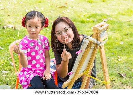Mother teach daughter painting with easel in garden