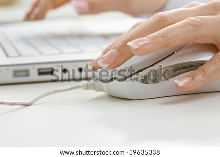 Closeup picture of computer keyboard and female hand clicks on mouse.