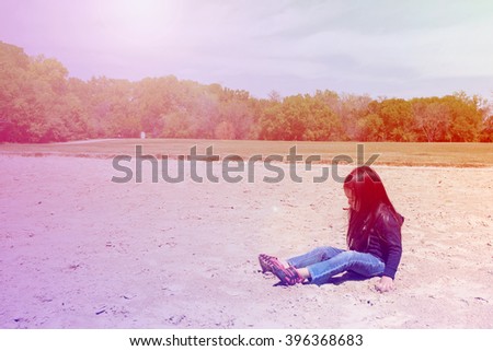 A happy little girl playing sand at public park with greenery background,filtered color tone in picture.