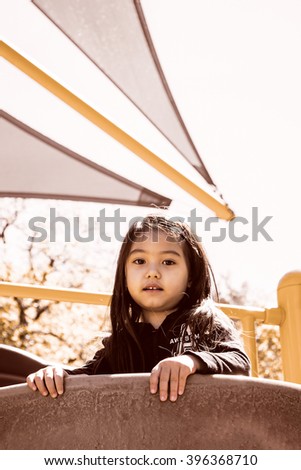 A happy little girl playing at public park with greenery background,filtered color tone in picture.