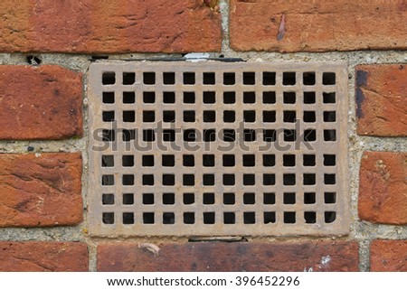 Red brick wall with a steel rectangular vent. Close-up straight view.