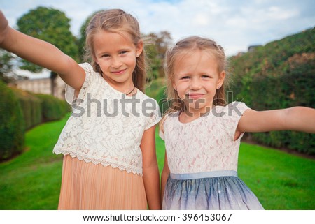 Adorable little girls taking selfie with mobile phone outdoors in Paris