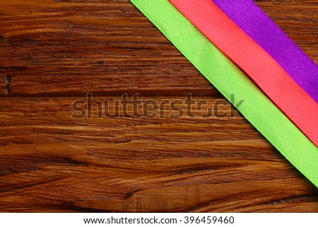 three silk ribbons for decoration lie on a wooden board