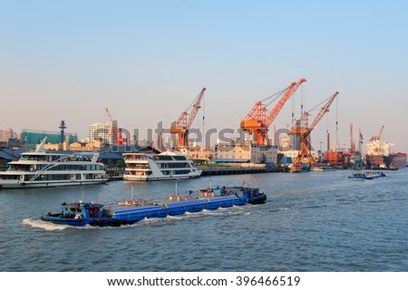 Boat in Huangpu River with Shanghai urban architecture and cargo crane 
