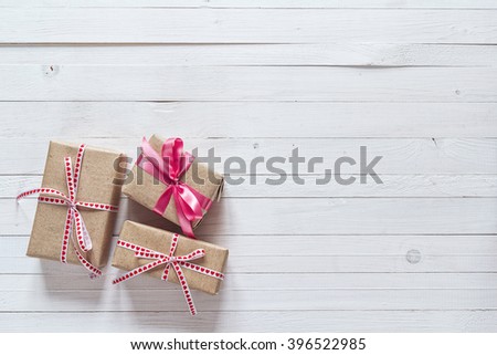 Gift boxes with pink ribbons on a white painted wooden background and empty space for text. Top view with copy space