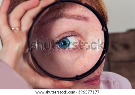 A young girl is looking through a big magnifier closeup
