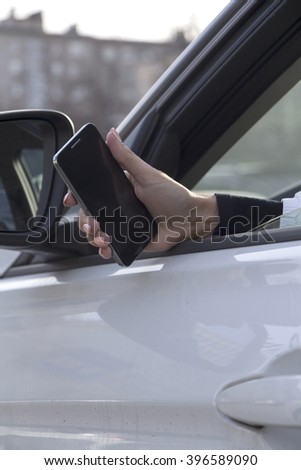 a girl takes pictures on a cell phone from the car window