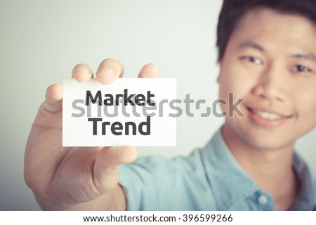 " Market Trend " word on card hold by smiling man