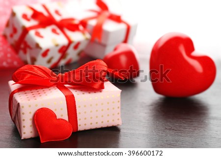 Gift boxes and decorative hearts on wooden table, on light background