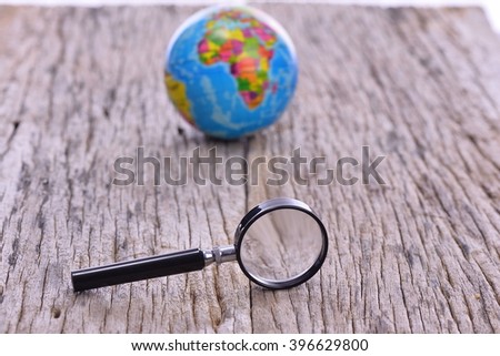 Map on Globe with magnifiying glass on wooden table. World globe
