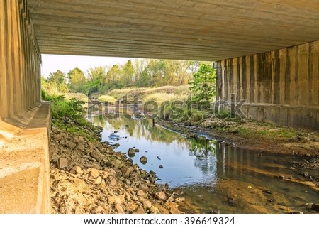 Under the bridge : Peaceful and Tranquil nature - river flowing through natural cascades and wet rock and sand with sunlight shining.