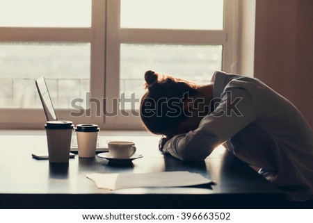 Overworked tired businesswoman sleeping on table in office. Young exhausted girl working from home. Woman using laptop. Entrepreneur, business, freelance work, student, stress, work from home concept Royalty-Free Stock Photo #396663502