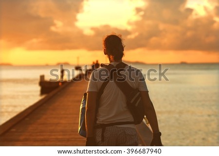 photographer at sunset is on the pier, a boat is going to sail to the core, to remove the sunset