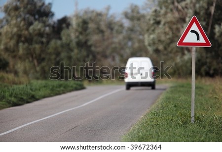 White pick-up going on a contryside road with a sharp corner sign on a lovely day